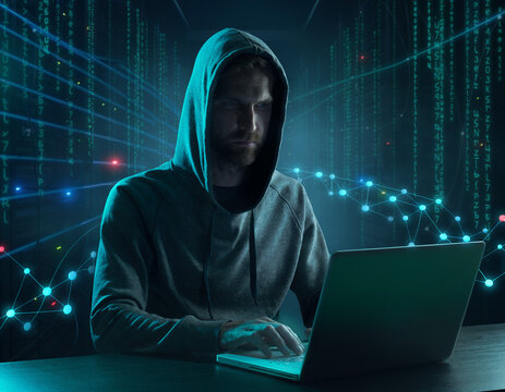 A hooded figure sits at a laptop surrounded by digital codes and futuristic network visuals, symbolizing cybersecurity threats or hacking activities.