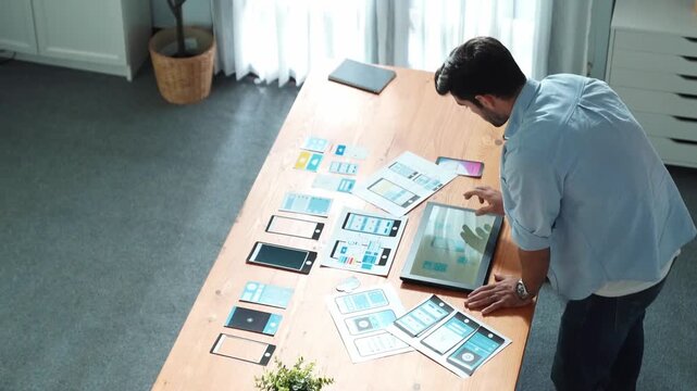 Top down view of handsome leader use laptop to analysis graph while marketing team working on tablet and looking at financial chart. Top view of startup group planning strategy together. Convocation.