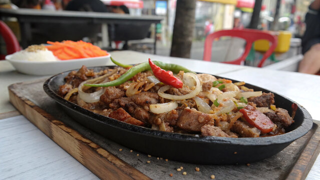 Photorealistic close-up of Filipino sisig with crisp browned pork, glossy onions, chili, calamansi and brittle pork-skin accents