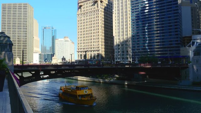 Scenic view of the Chicago River flowing through downtown, featuring iconic skyscrapers, historic bridges, and tour boats navigating the urban waterway on a sunny day.