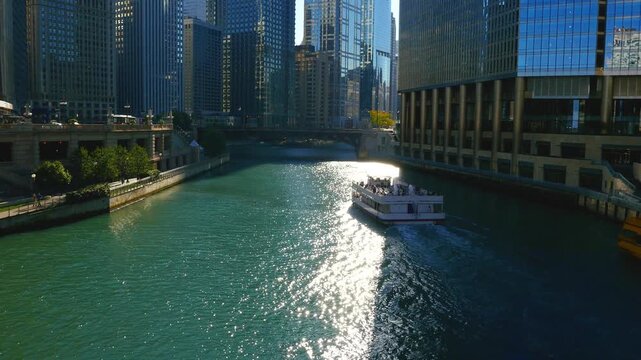 Scenic view of the Chicago River flowing through downtown, featuring iconic skyscrapers, historic bridges, and tour boats navigating the urban waterway on a sunny day.