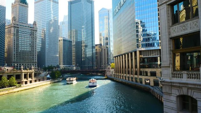 Scenic view of the Chicago River flowing through downtown, featuring iconic skyscrapers, historic bridges, and tour boats navigating the urban waterway on a sunny day.