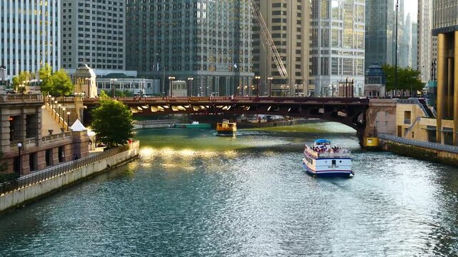 Scenic view of the Chicago River flowing through downtown, featuring iconic skyscrapers, historic bridges, and tour boats navigating the urban waterway on a sunny day.