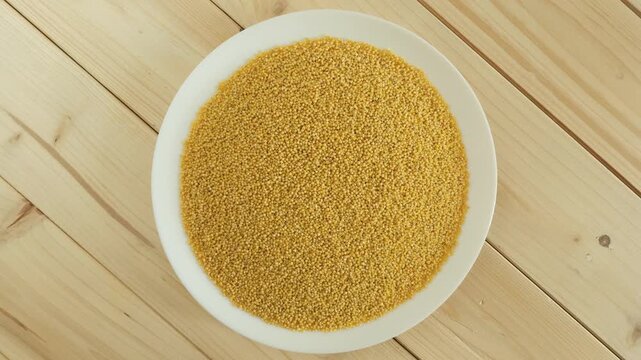Raw millet grains rotating on a white plate