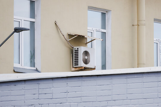White AC unit on facade with open window in hot weather. High quality photo.
