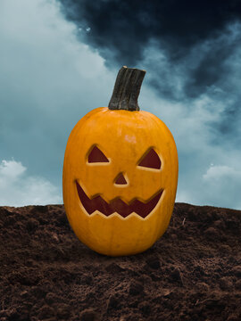Carved jack o lantern pumpkin on dirt ground against a spooky cloudy sky
