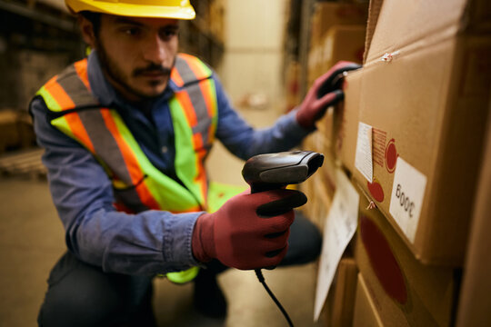 Close up of worker scanning labels while checking packages in distribution warehouse.