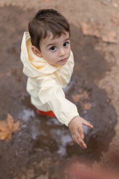 Toddler in raincoat reaching out for help