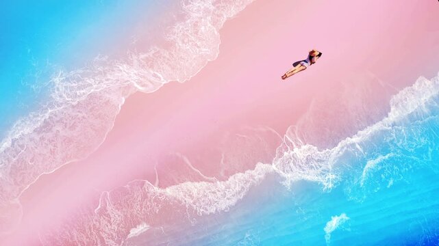Top down drone view of woman freelance digital nomad working on laptop on pink sand beach. Aerial shot of remote business lifestyle lying on exotic tropical ocean shore during summer vacation.