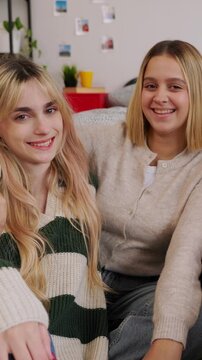 Vertical HD video of two young adult female friends sitting together in a bedroom. Portrait of happy Gen Z women relaxing and bonding at home. Friendship and lifestyle concept. 