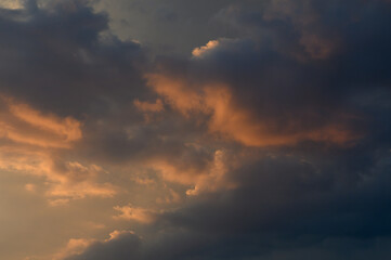 Fototapeta premium Sunset skyscape filled with dark storm clouds and warm golden highlights
