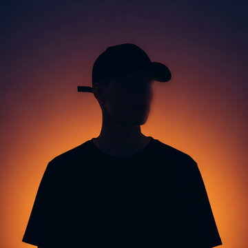 Silhouette of a person wearing a baseball cap and t-shirt against a vibrant sunset gradient background