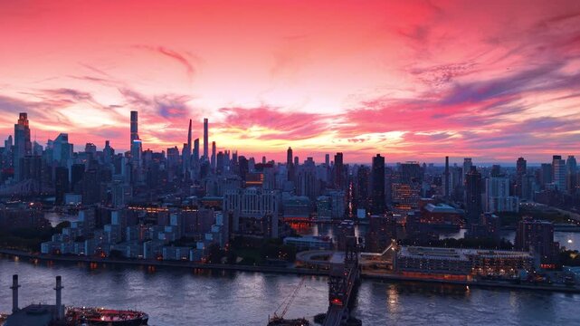 Thriving urban city against pink sky. Rising over the river waterfront at dusk time. New York City, USA.