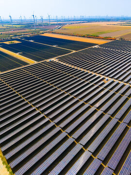Rows of solar panels on agricultural ground area. Vertical high angle perspective of solar panel installation surrounded by agricultural fields.