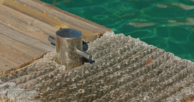 the edge of a wooden pier in one of the bays of Turkey, thick ropes and fasteners for a sailing boat, azure water on a sunny day