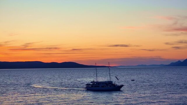Yacht silhouette coming back to the harbor, at sunset