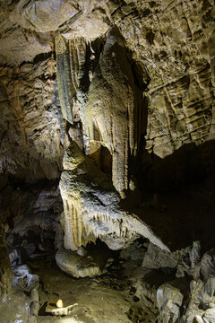 Vertical view of a massive illuminated stalactite pillar and rock formations inside the Lurgrotte cave in Peggau, Styria, Austria