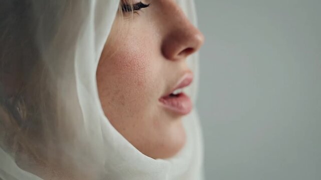Close up portrait of woman wearing white headscarf.