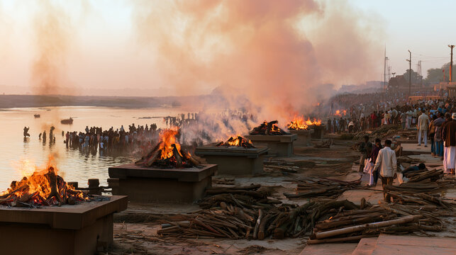 Wide view of several Hindu Antyesti funeral pyres burning simultaneously on raised stone platforms at a historic cremation ghat, orange flames and dense smoke rising while mourners