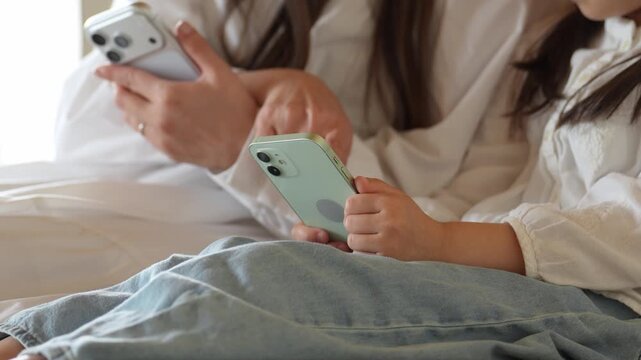リビングでスマートフォンを使う女の子とお母さん