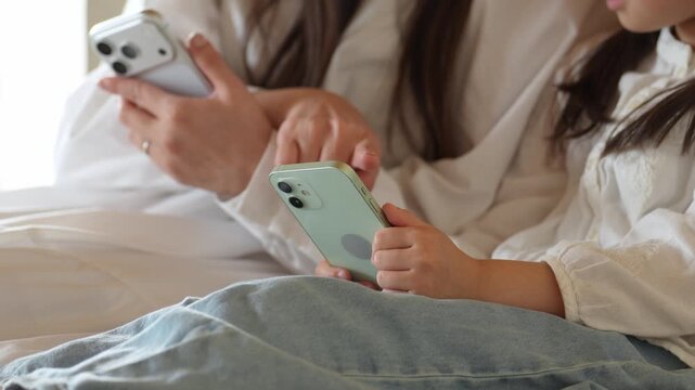リビングでスマートフォンを使う女の子とお母さん