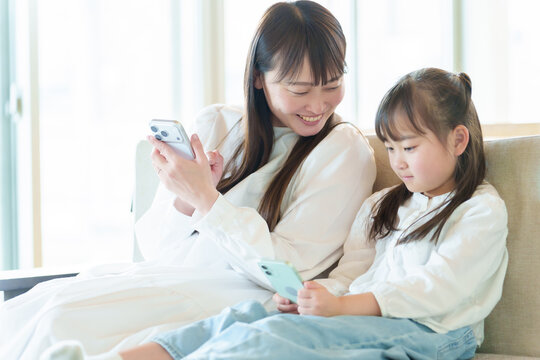 リビングでスマートフォンを使う女の子とお母さん