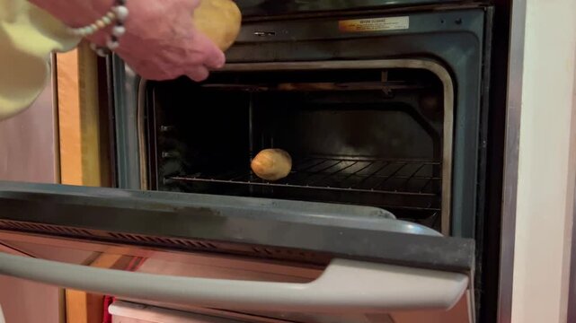 Person placing potatoes on wire rack inside oven to bake