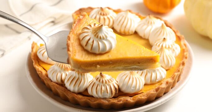 Taking and showing piece of delicious pumpkin pie with meringue at wooden table, closeup. Pastry for Thanksgiving day or other fall holiday