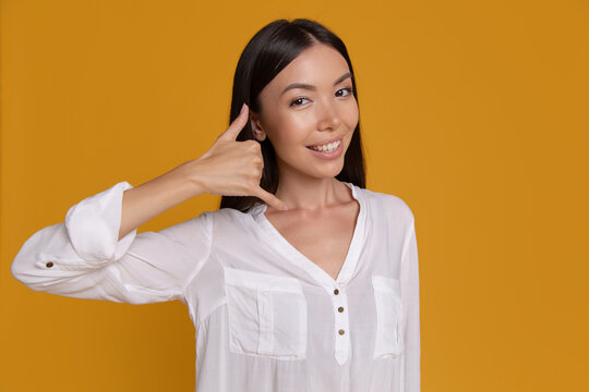Smiling woman making call me hand gesture
