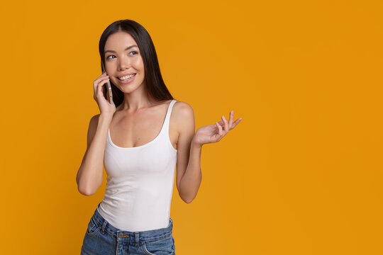 Woman talking on smartphone and gesturing beside copy space