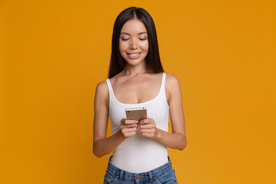 Happy woman messaging on smartphone and using mobile app