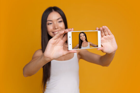 Woman showing smartphone screen with selfie camera preview