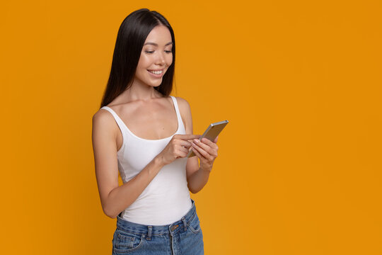 Smiling woman using smartphone beside large copy space