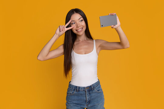 Happy woman taking selfie and showing peace sign