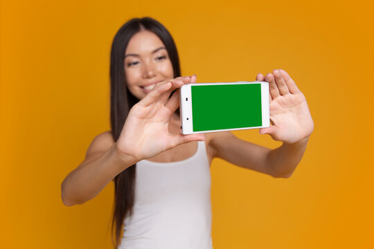 Woman presenting smartphone with green screen mockup