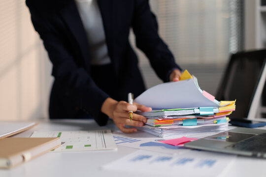 Businesswoman managing, sorting, and organizing documents, papers, and folders on an office desk, illustrating administrative tasks, accounting, and taxation work