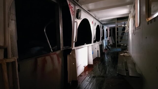 Side deck steel fishing boat underway on rough sea at night
