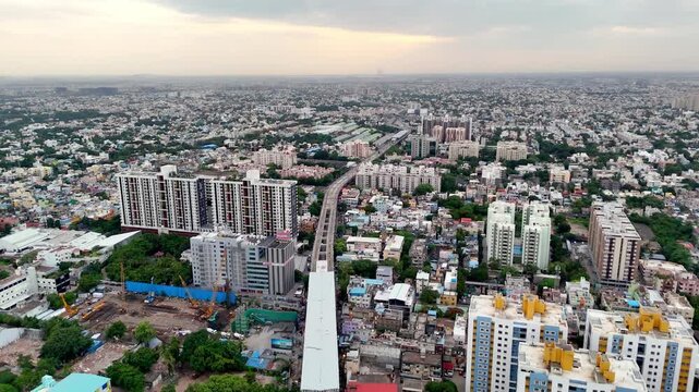 Cinematic aerial view of Kodambakkam, Chennai, showcasing a dense urban landscape with elevated metro infrastructure, high-rise residential towers, commercial buildings, colorful neighborhoods