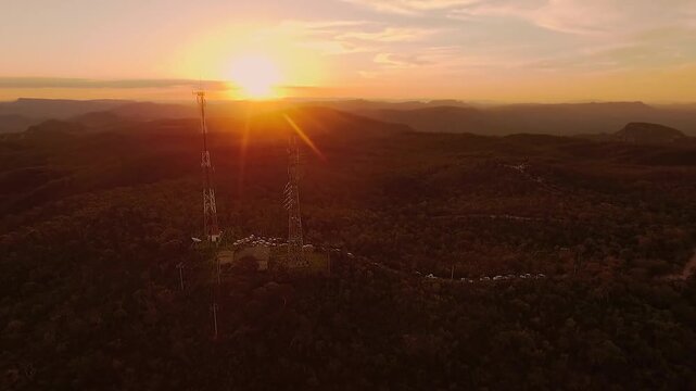 Telecommunication towers stand above the Cerrado and distant plateaus near Sao Jorge in Alto Paraiso de Goias, Goias, Brazil, drone orbital movement.