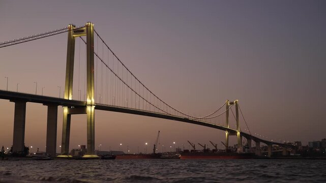 Dramatic view at dusk of the iconic Maputo-Katembe Bridge spanning the water near the busy port