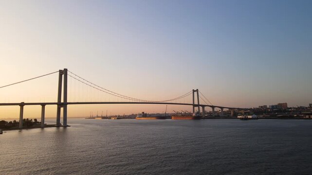 Drone scene highlighting the iconic Maputo-Katembe Bridge and Port with a beautiful golden sunset in the background