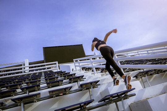 Runners practice stair running to improve their physical strength..Woman runner running sprinting up stairs at stadium.