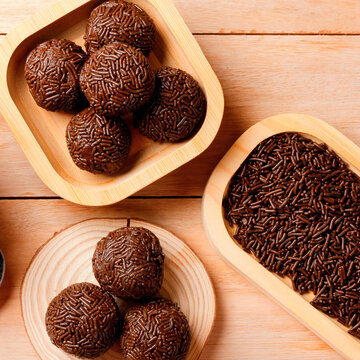 Brazilian chocolate brigadeiro topped with sprinkles, arranged on a rustic bamboo tray on a wooden table.