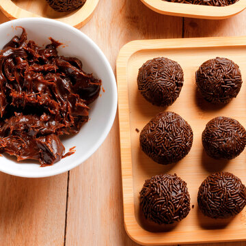 Classic Brazilian brigadeiro coated in chocolate sprinkles, served on a rustic bamboo tray and set on a wooden surface.