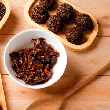 Brazilian sweet known as brigadeiro, coated in chocolate sprinkles and arranged on a bamboo tray on a wooden table.