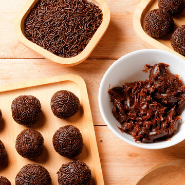 Traditional Brazilian chocolate brigadeiro with chocolate sprinkle coating, featured on a bamboo tray and set on a wooden table.