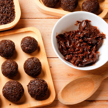 Traditional Brazilian chocolate brigadeiro, served on a bamboo tray and arranged on a wooden table.
