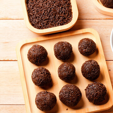 Handmade chocolate brigadeiro with sprinkles a signature Brazilian confection presented on a bamboo tray on a wooden table.