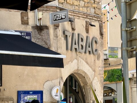 bourg-en-bresse, France - may 20 2026: A stone building facade displays a Tabac sign and FDJ lottery sign. A black awning shades the Place Claudinet street sign.