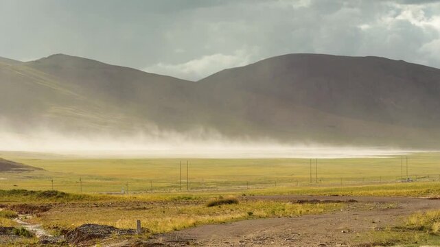 Sand storm moving by wind on grass field like wall with mountains background, 4k slow motion footage environment concept b roll shot.